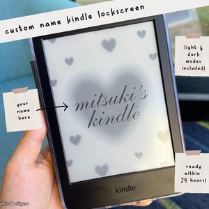 May include: A black and white Kindle e-reader with a custom lockscreen design. The design features a heart with the text "mitsuki's kindle" and a background of hearts. The text "your name here" is written on a sticky note.