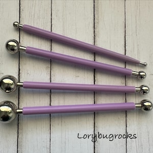 May include: Four purple handled ball stylus tools with silver metal balls of varying sizes. The tools are arranged in order of size from largest to smallest.