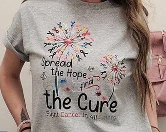 May include: Gray t-shirt with a design of two dandelions made of colorful ribbons. The text "Spread the Hope find the Cure" is printed on the shirt. Below the text is the phrase "Fight Cancer In All Colors".