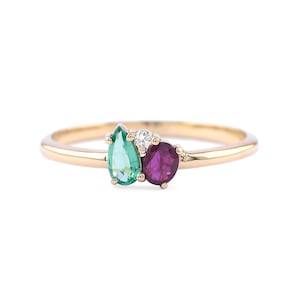 May include: A gold ring featuring a pear-shaped emerald, a round ruby, and a small round diamond.