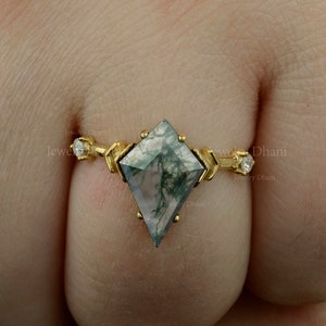 Op de afbeelding: Een gouden ring met een groene en witte mosagaat edelsteen in een vlieger vorm. De ring heeft twee kleine diamanten aan elke kant van de edelsteen.