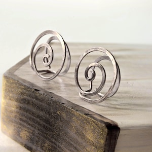 Könnte beinhalten: Ein Paar silberne Ohrringe mit einem Spiraldesign. Die Ohrringe sind aus Draht gefertigt und haben eine gehämmerte Oberfläche.