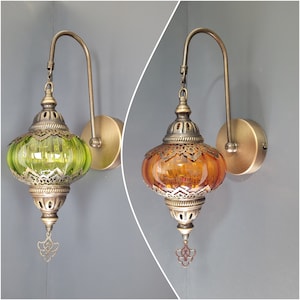 May include: Two wall sconces with ornate metalwork and glass shades. One shade is green and the other is amber.