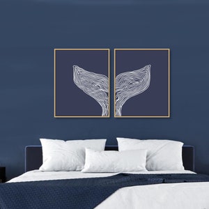 May include: Two framed prints of a white line drawing of a whale tail on a dark blue background.