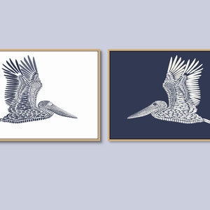 May include: Two framed prints of a stylized pelican in flight, one with a white background and the other with a dark blue background. The pelican is made up of small, repeating shapes.