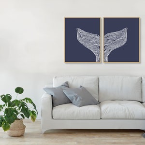 May include: Two navy blue framed prints with a white line drawing of a whale tail on each print.