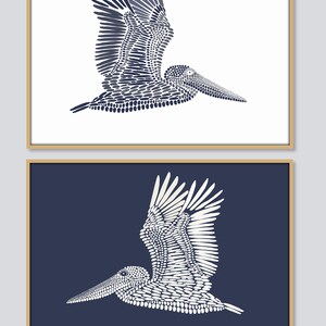 May include: Two framed prints of a stylized pelican made of dots. The pelican is in flight with its wings spread. The top print has a white background and the pelican is navy blue. The bottom print has a navy blue background and the pelican is white.