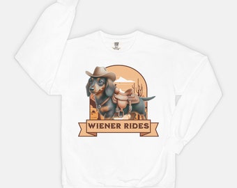 May include: White long-sleeve sweatshirt with a cartoon image of a dachshund wearing a cowboy hat and riding a saddle. The text "Wiener Rides" is printed on a brown banner below the image.