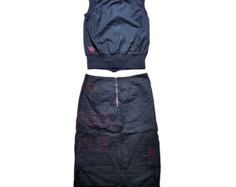 May include: A black sleeveless top with a pinstripe pattern and a black skirt with the words "2016 PEOPLE" embroidered in pink. The skirt has a zipper down the back.