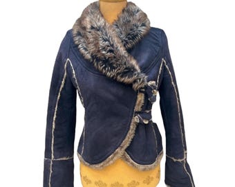 May include: A dark blue faux fur jacket with a large, brown faux fur collar. The jacket has a belted waist and long sleeves.