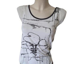 May include: White sleeveless shirt with a black and white abstract graphic print. The text "Top Copine" is visible on the shirt.