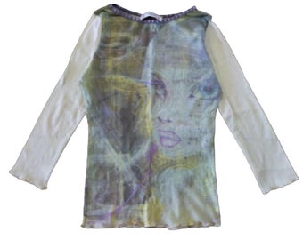 May include: White long-sleeved shirt with a sheer overlay featuring a colorful abstract design with a woman's face.