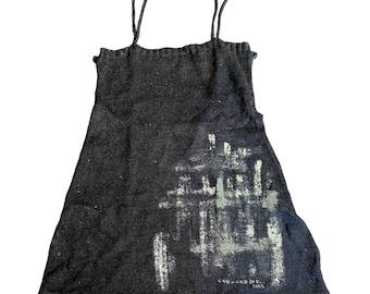 May include: A black camisole with thin straps and a slightly ruffled neckline. The garment features a faded white graphic print on the front and the text "GIVENCHY PARIS".