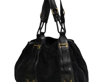 Pode incluir: Bolsa tote de couro preto com ferragens douradas e um design estampado em preto e branco.