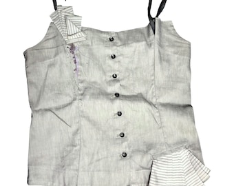 May include: A gray linen tank top with a button-up front and a ruffled detail on the shoulder and hem. The top has a striped pattern on the ruffle.