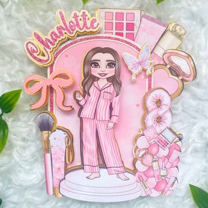 Personalized makeup-themed cake topper featuring a girl in pink striped pajamas surrounded by beauty and spa accessories including makeup brushes, lipstick, blusher, eyeshadow, skincare items, and a pink bow. The topper is decorated in pink glitter card and gold mirror  with the name and age of the birthday girl, making it perfect for a glam birthday, spa party, or makeup-themed celebration.
