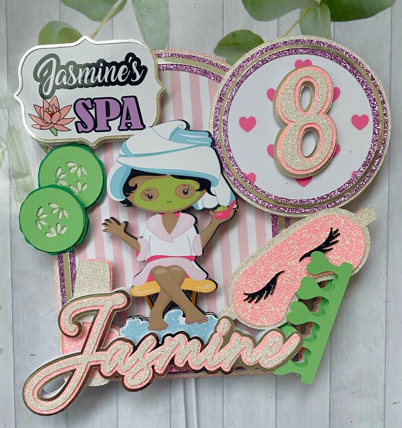 Puede incluir: Adorno para tarta con tem&aacute;tica de spa con el texto "Jasmine's SPA" y un personaje de dibujos animados con mascarilla y toalla. El adorno incluye un fondo a rayas rosas y blancas, rodajas de pepino y el n&uacute;mero 8 con corazones.