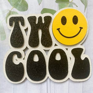 May include: A decorative sign featuring the words "THX COOL" in black glitter letters, outlined with white glitter. A yellow smiley face is on the right. Suitable for home decor or as a gift.
