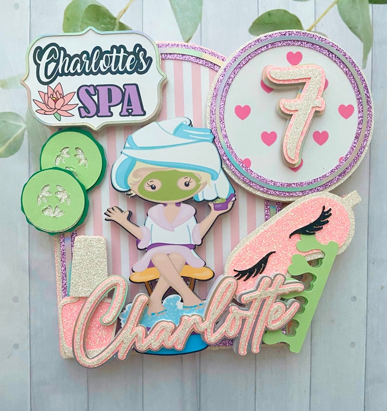 Puede incluir: Adorno para tarta con tem&aacute;tica de spa con el texto "Charlotte's SPA" y una ni&ntilde;a de dibujos animados con mascarilla. Incluye rodajas de pepino, el n&uacute;mero 7 y el nombre "Charlotte". El dise&ntilde;o utiliza acentos rosas, blancos, verdes y brillantes.