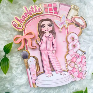 Personalized makeup-themed cake topper featuring a girl in pink striped pajamas surrounded by beauty and spa accessories including makeup brushes, lipstick, blusher, eyeshadow, skincare items, and a pink bow. The topper is decorated in pink glitter card and gold mirror  with the name and age of the birthday girl, making it perfect for a glam birthday, spa party, or makeup-themed celebration.