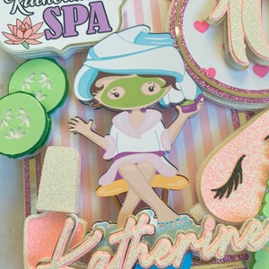 Puede incluir: Adorno para tarta con tem&aacute;tica de spa con el texto "Katherine's SPA" y un personaje de dibujos animados con mascarilla y toalla. Incluye rodajas de pepino, un frasco de esmalte de u&ntilde;as y el n&uacute;mero 10. Acentos rosas, blancos y dorados.