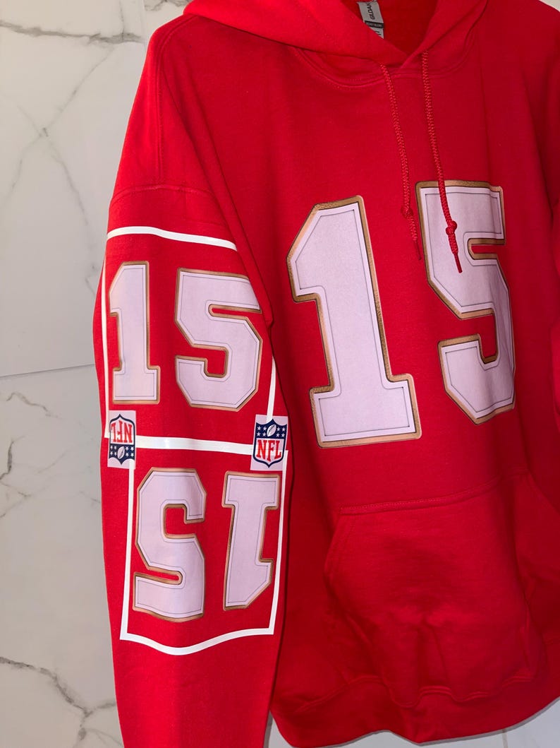 Puede incluir: Sudadera con capucha roja con el n&uacute;mero 15 en blanco con ribete dorado en la parte delantera y la manga. La manga tambi&eacute;n presenta dos logotipos de la NFL. La sudadera tiene un bolsillo delantero y una capucha con cord&oacute;n.