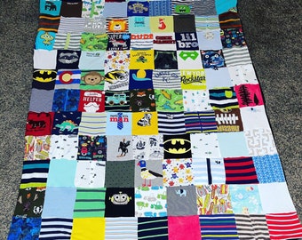 May include: A colorful patchwork quilt made from a variety of baby clothes. The quilt is made up of squares of different colors and patterns, including blue, green, red, yellow, and white. Some of the squares feature cartoon characters and other designs. The quilt is a great way to commemorate a baby's first year.