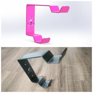 May include: Two bike hooks, one pink and one black, with a bicycle silhouette design. The hooks are made of metal and are designed to be mounted on a wall.