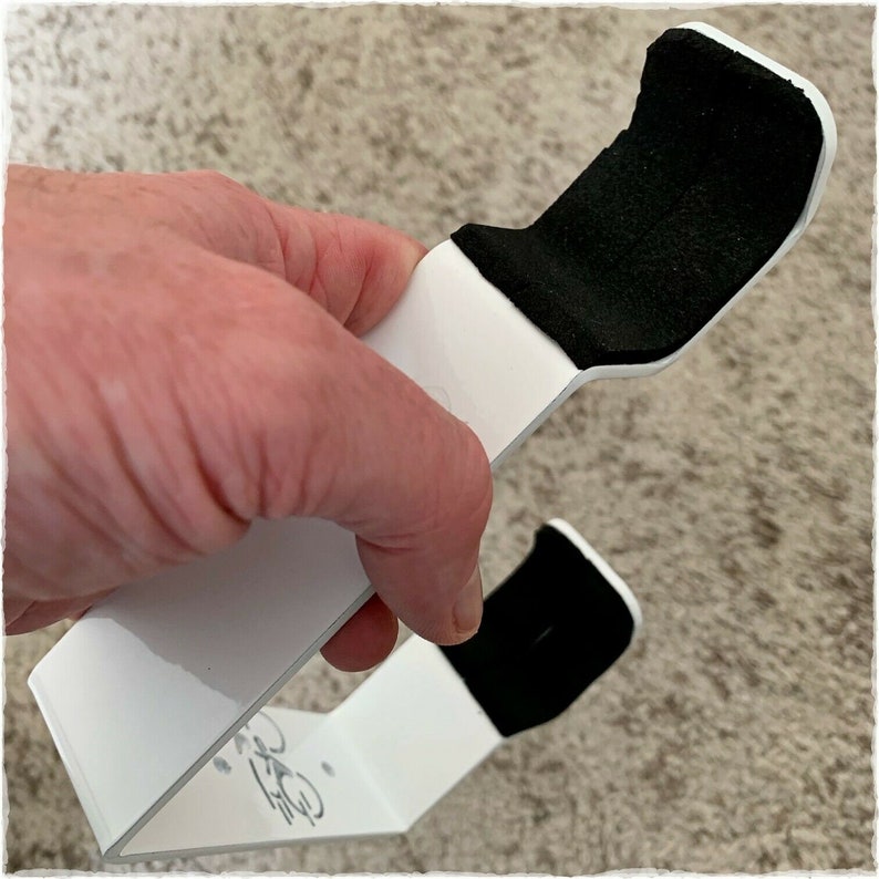 May include: White plastic hook with black felt padding on the top and bottom. The hook is designed to hold a bag or other object.