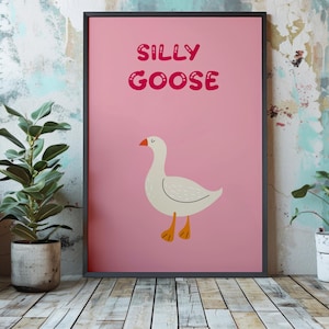 以下が含まれることがあります： ピンクのポスターに、バブルのようなフォントで「Silly Goose」という文字が書かれています。ポスターには、オレンジ色の足をした白いガチョウが描かれています。