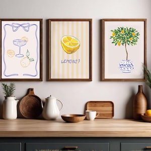 Könnte beinhalten: Drei gerahmte Illustrationen mit Zitronen-Motiv. Die erste Illustration zeigt ein Glas Limonade mit Zitronen. Die zweite Illustration zeigt eine Zitronenscheibe mit dem Text "LEMONS?" Die dritte Illustration zeigt einen Zitronenbaum in einem blau-weißen Topf.