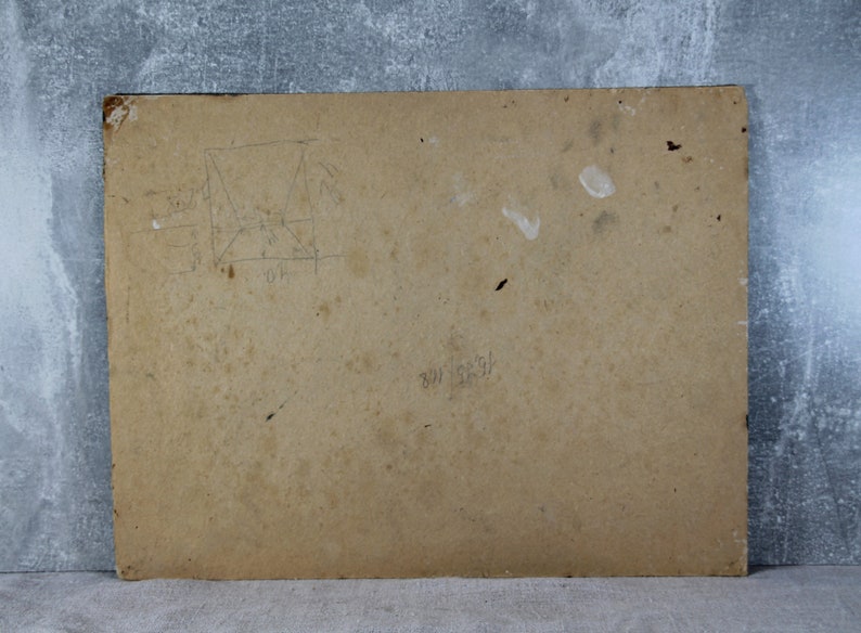 May include: The back of a brown cardboard picture frame with some faint pencil markings and a few white smudges.