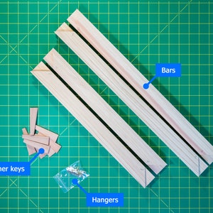 May include: Three wooden bars, corner keys, and hangers for a picture frame. The bars are light brown and the corner keys are small, triangular pieces of wood. The hangers are metal and are in a clear plastic bag.
