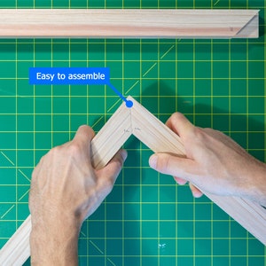 May include: A person assembling a wooden frame. The frame is made of light wood and has a green background. The text "Easy to assemble" is written on a blue banner.