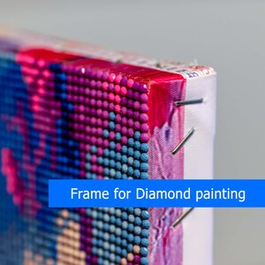 May include: Close-up of the edge of a diamond painting canvas, showing the colorful rhinestones and the frame. The canvas is stretched and secured with staples. The text "Frame for Diamond painting" is visible on a blue banner.