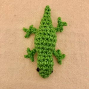 May include: A green crocheted lizard toy with black eyes.