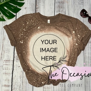 Puede incluir: Una camiseta marrón con un diseño salpicado de lejía. La camiseta tiene un círculo en el centro con el texto "YOUR IMAGE HERE". El texto "The Occasional Tee Company" está en la parte inferior de la camiseta.