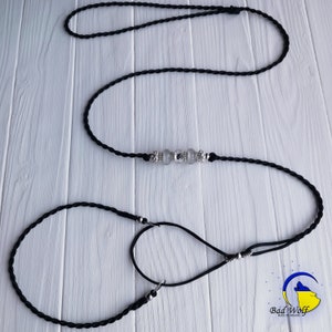 May include: Black braided dog leash with a silver clasp and clear crystal beads. The leash is made of two separate pieces, one longer than the other.