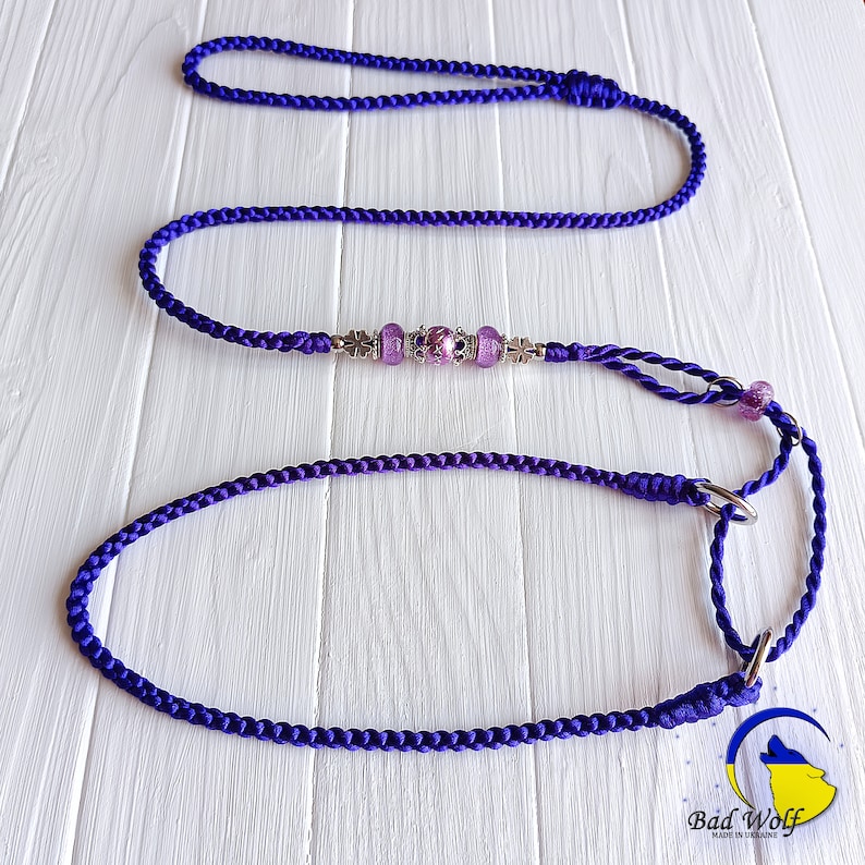 May include: Purple braided dog leash with silver and purple beads and two metal clasps. The leash is on a white wooden surface. "Bad Wolf Made in Ukraine" is printed on the bottom right corner of the image.