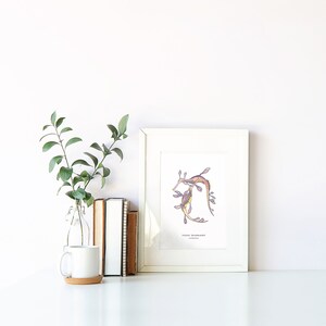 K&ouml;nnte beinhalten: Ein gerahmter Druck einer Aquarellillustration von zwei Weedy Seadragons, einer Fischart, in Violett-, Gelb- und Oranget&ouml;nen. Der Druck ist auf wei&szlig;em Hintergrund und hat den Text "Weedy Seadragon" und "Australia" unter der Illustration.