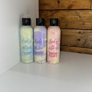 May include: Three bottles of body lotion with different scents. The bottles are clear with a white swirl design. The labels are white with black text. The scents are "Tequila and Wishes", "Jamaican Me Crazy", and "Snow Fairy".