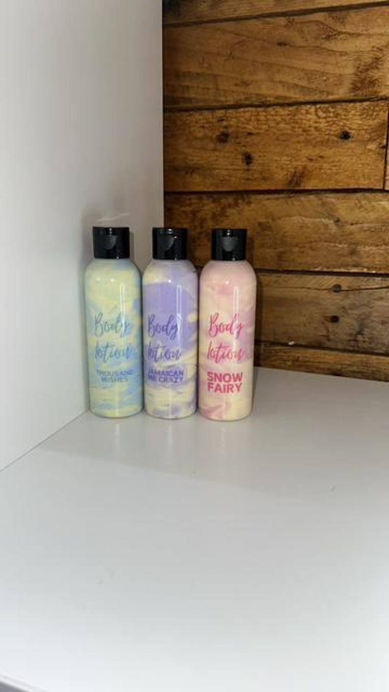 May include: Three bottles of body lotion with different scents. The bottles are clear with a white swirl design. The labels are white with black text. The scents are "Tequila and Wishes", "Jamaican Me Crazy", and "Snow Fairy".
