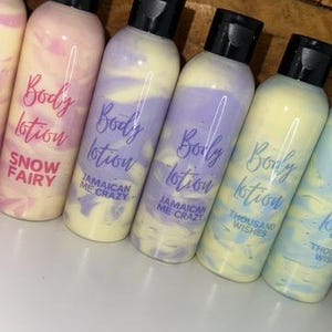 May include: Five bottles of body lotion with different scents. The bottles are clear with a swirl of color inside. The labels are white with purple text that says "Body Lotion" and the scent name. The scents are "Snow Fairy", "Jamaican Me Crazy", "Jamaican Me Crazy", "Thousand Wishes", and "Thousand Wishes".