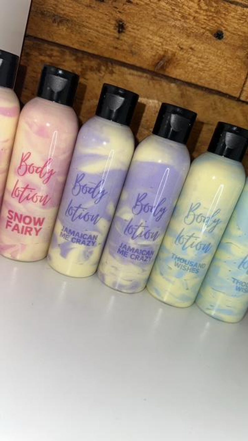 May include: Five bottles of body lotion with different scents. The bottles are clear with a swirl of color inside. The labels are white with purple text that says "Body Lotion" and the scent name. The scents are "Snow Fairy", "Jamaican Me Crazy", "Jamaican Me Crazy", "Thousand Wishes", and "Thousand Wishes".