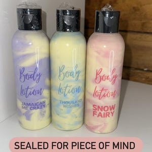 May include: Three sealed bottles of body lotion with colorful swirls. The bottles are labeled "Body Lotion" with different scents: "Jamaican Me Crazy", "Thousand Wishes", and "Snow Fairy".