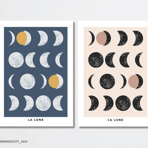 May include: Two art prints featuring moon phase illustrations. One print has a navy blue background with white and yellow moons, the other has a beige background with black and pink moons. Both prints have the text "LA LUNE".