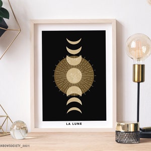 May include: A black and gold minimalist print with a stylized sun and moon phases. The text "LA LUNE" is at the bottom of the print.