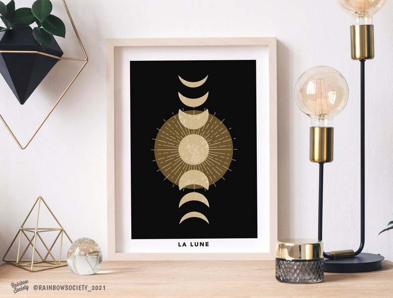 May include: A black and gold minimalist print with a stylized sun and moon phases. The text "LA LUNE" is at the bottom of the print.