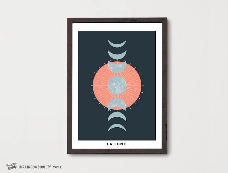 May include: A framed print with a dark blue background featuring a stylized moon design with a peach-colored circle in the center and a crescent moon design in various phases. The text "LA LUNE" is at the bottom of the print.