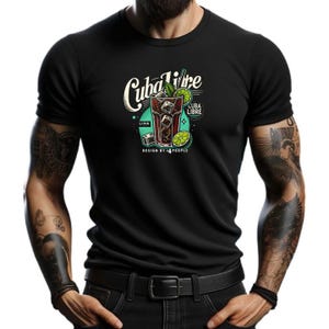 Puede incluir: Camiseta negra con un diseño gráfico de un cóctel Cuba Libre. El diseño presenta un vaso con hielo, lima y una ramita de menta. El texto "Cuba Libre" está escrito en una fuente de estilo vintage. El texto "Lima" y "Cuba Libre" también están incluidos en el diseño.